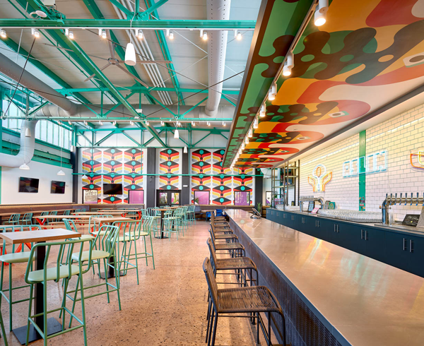 neon signs flash against white tiles at the bar of this brewery