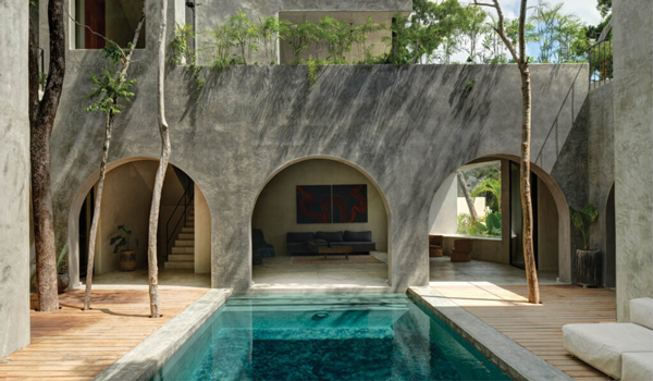 A meditative pool in front of brutalist archways in a modern hacienda