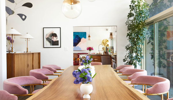 pink velvet chairs line a long wooden dining table