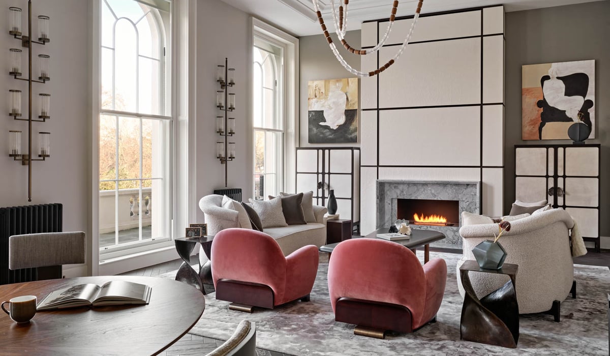 pink armchairs and white sofas in front of a fireplace