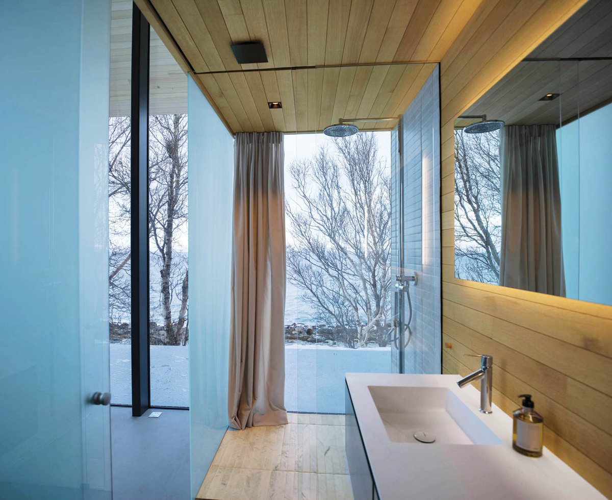 A glass-walled bathroom with snowy views