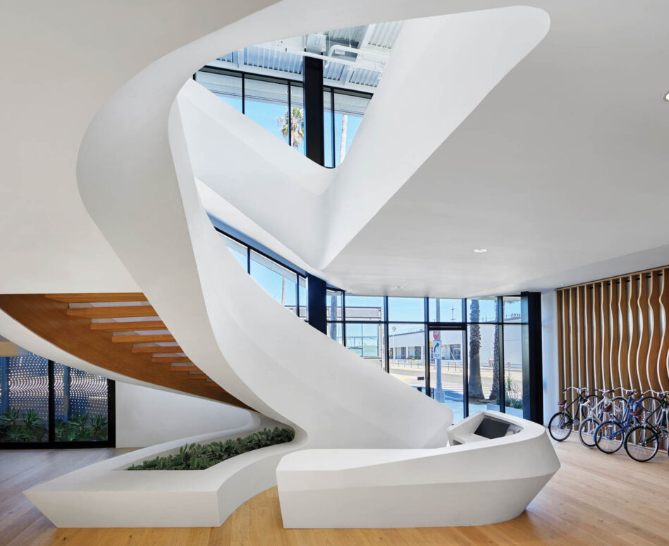 a winding white staircase near a wall of bikes