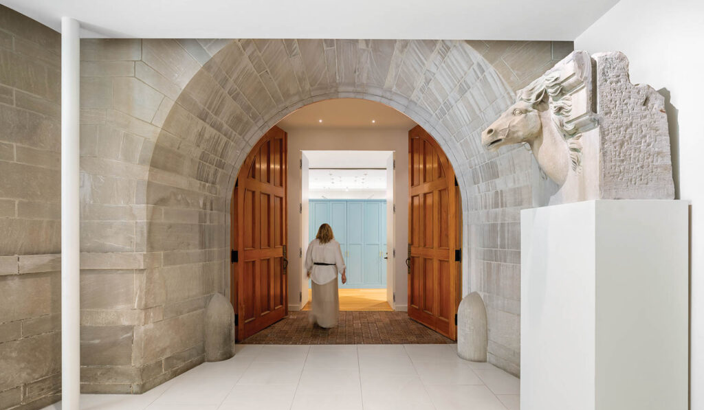 a woman walks through an arched hallway 