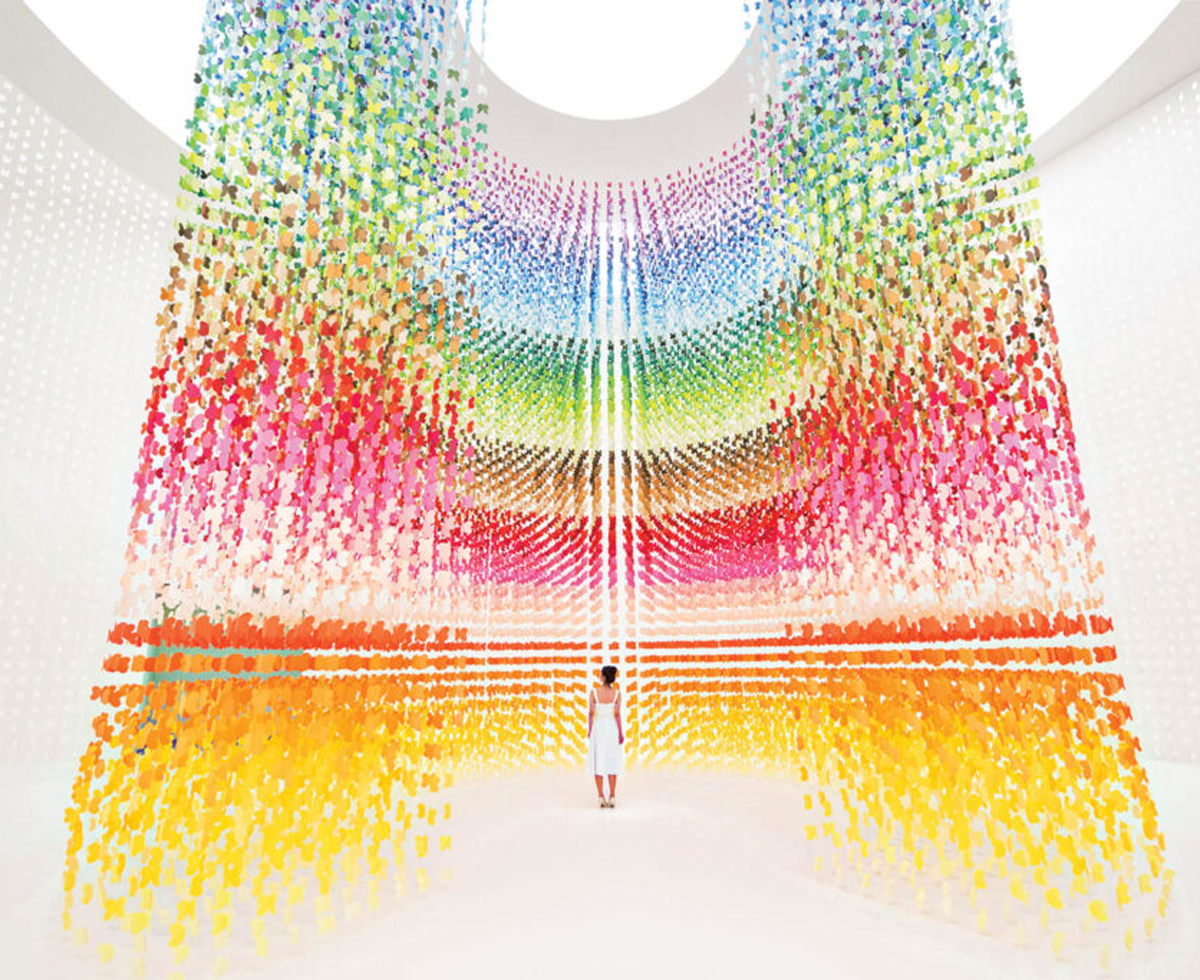 person standing in front of rainbow butterfly display that stretches up to the ceiling