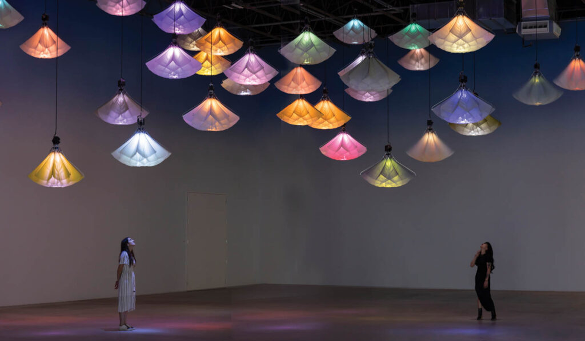 two people in room staring up at multicolored lanterns