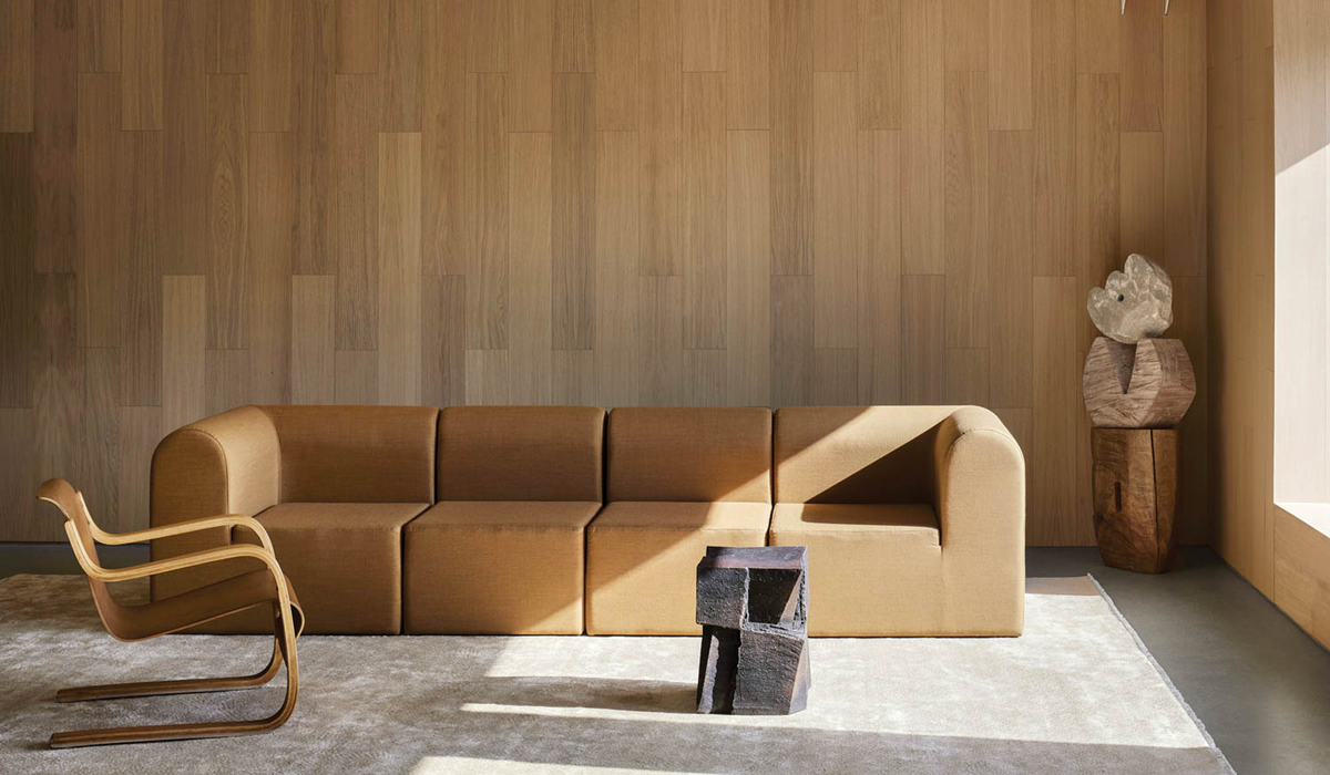 living room with tan couch, rugs, wooden wall