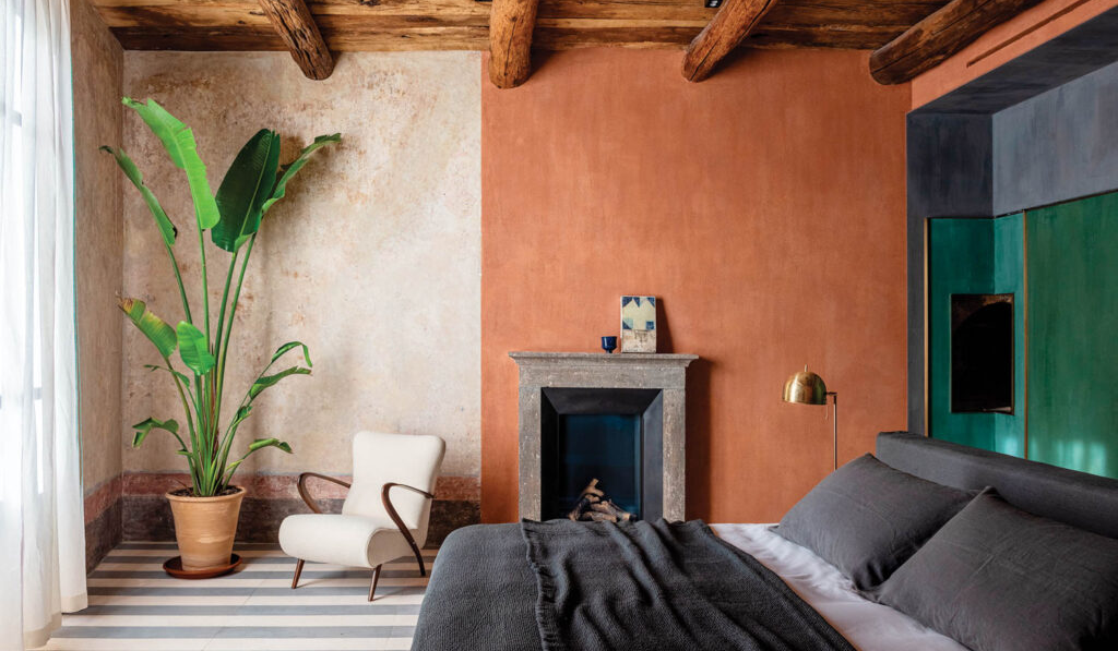 bedroom with tan and white walls, wooden beamed ceiling and plant in corner