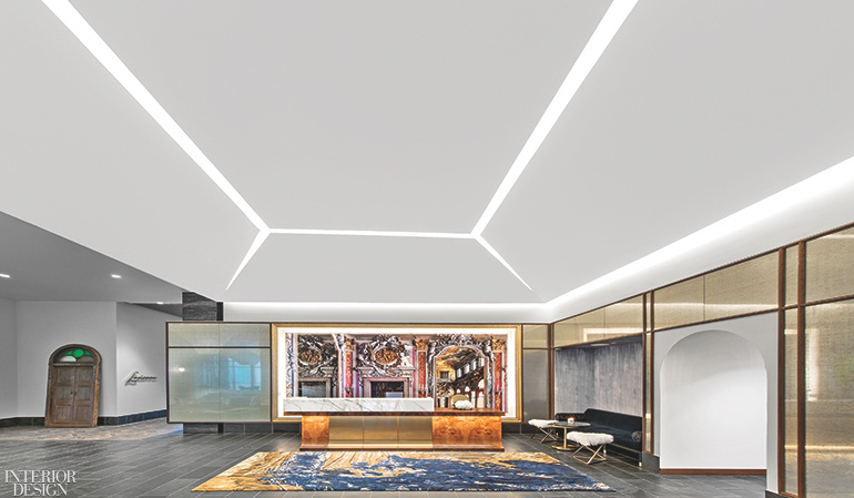 A hotel reception area with an expansive white ceiling grounded by an orange and blue rug. 