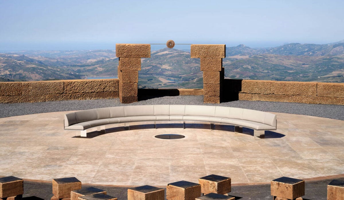 a curved sofa on an outdoor patio overlooking mountains