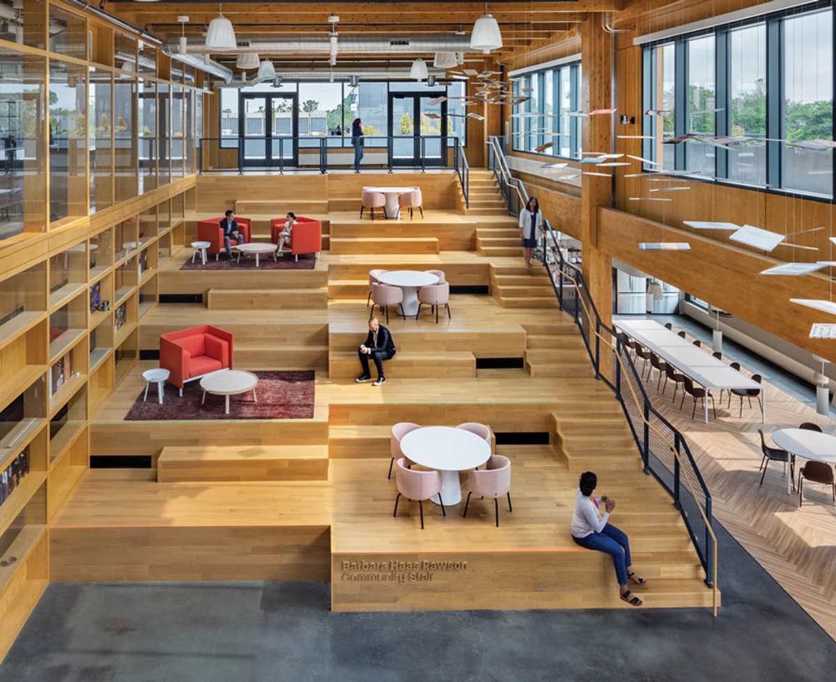 people sitting on layered wooden platforms along a staircase with views to the city