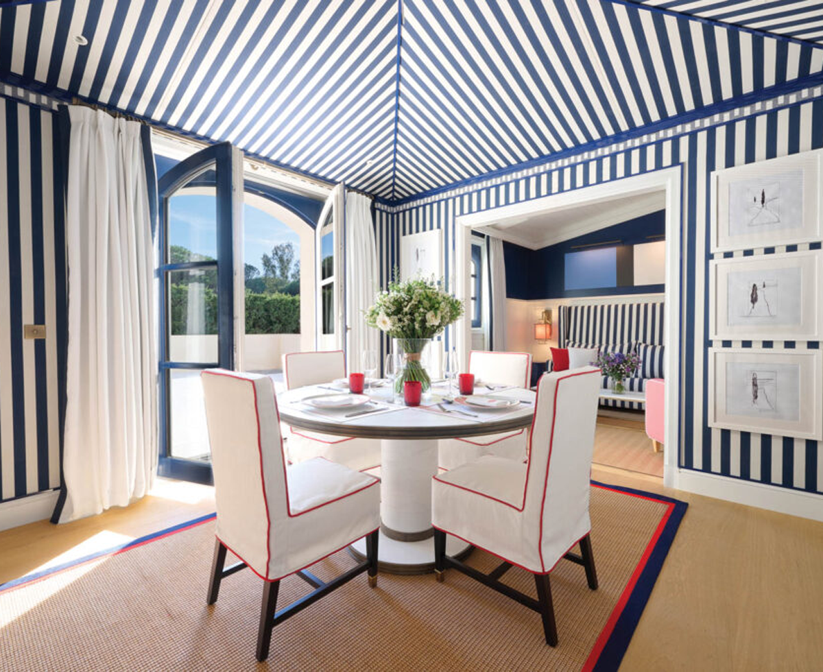 dining area of a room in the Arev Saint Tropez underneath a striped canopy and with french doors open to the outdoors