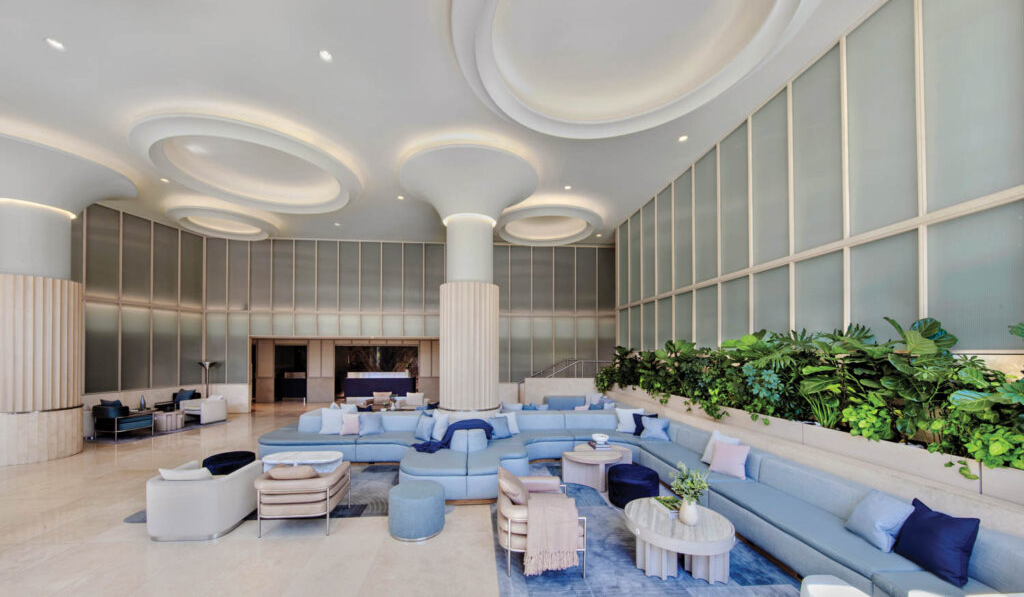 lobby of the Morrow Hotel with mint green glass panels along the walls and light blue settees