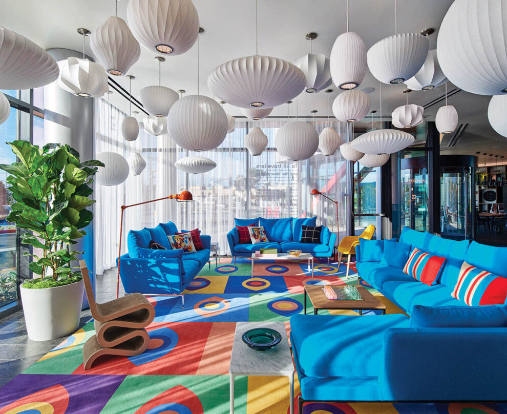 sitting room with colorful carpet, bright blue couches and white lamps