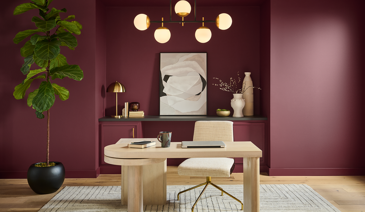 home office with dark red walls, wooden desk and chandelier