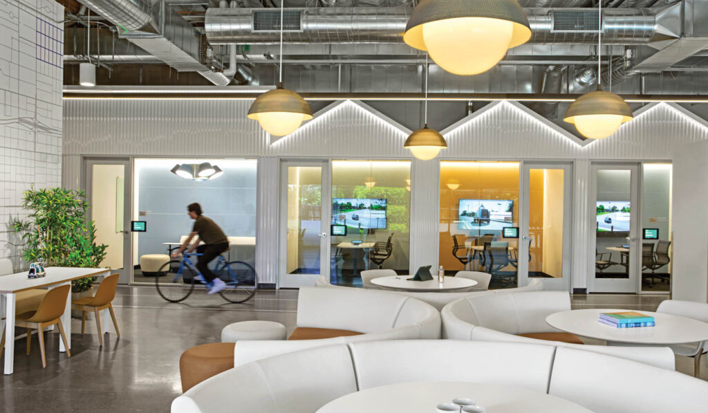 a man bikes through a tech office with white curved couches