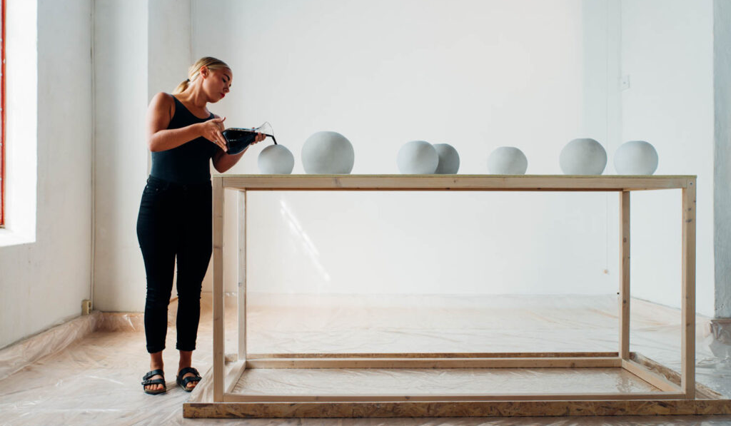 a woman leaning on a table with white ceramic orbs