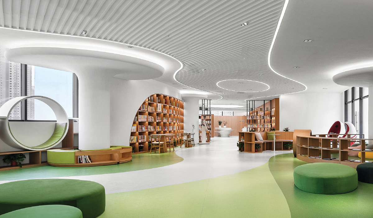 interior of library with varying shades of green flooring, green ottomans and bright lit ceilings