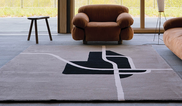 a windowed room with an area rug and armchair