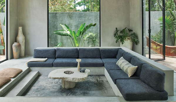 A sitting area with a gray sectional and concrete floors