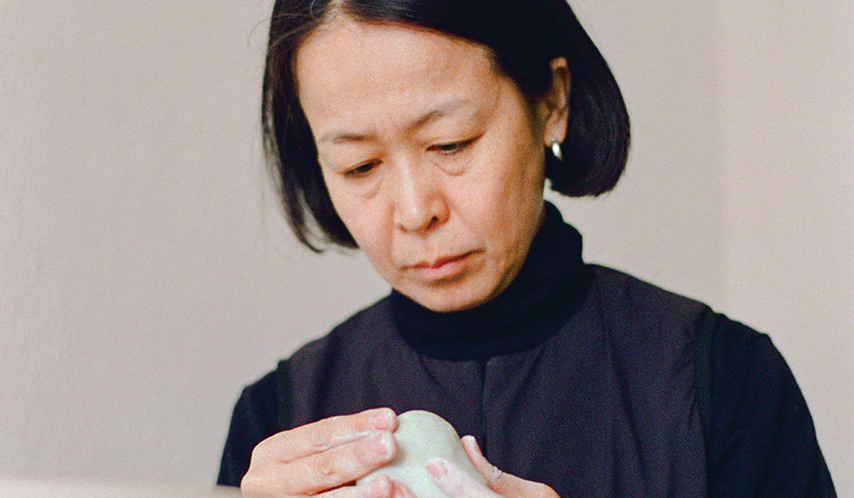 a woman in a black turtleneck holding clay