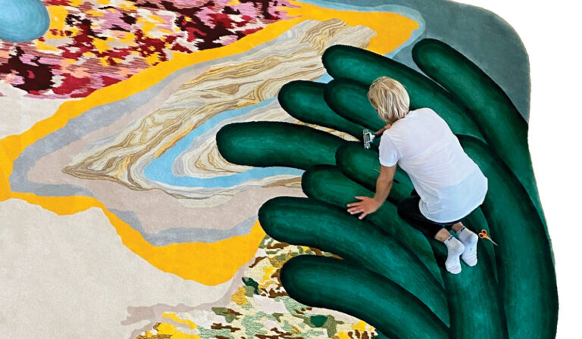 Artist standing over her surreal rug that looks like earth topographies