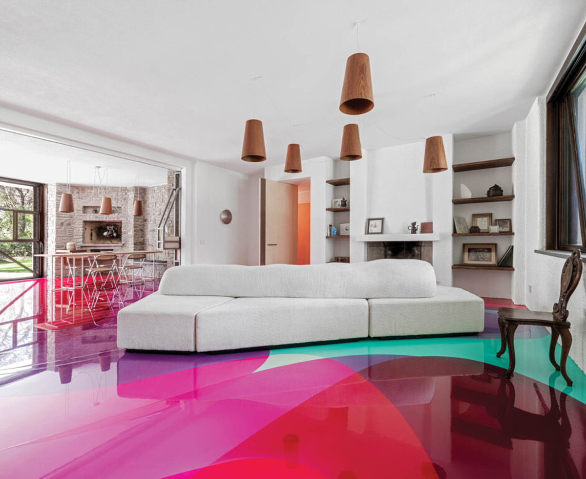 living room with bright lacquered pink and green floor, white couch and hanging lights