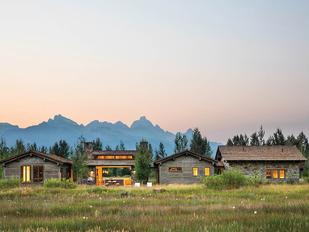 a rustic home with mountains in the background at dusk
