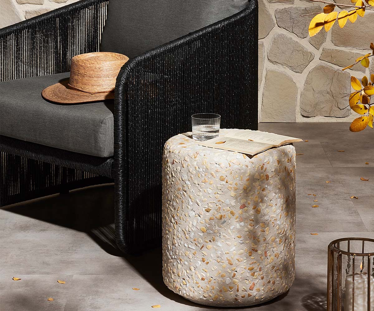 An outdoor chair with black upholstery and a round stone table.