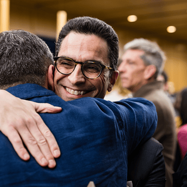 A close-up shot of two men hugging at an event